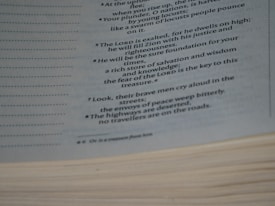 A close-up image of a page from a book reveals text in a poetic or biblical style, detailing themes of justice, righteousness, and desolation in times of trouble. The page edges are visible, and the text is written in a clear, readable font with italics for emphasis.