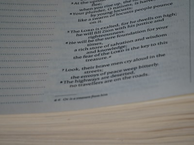 A close-up image of a page from a book reveals text in a poetic or biblical style, detailing themes of justice, righteousness, and desolation in times of trouble. The page edges are visible, and the text is written in a clear, readable font with italics for emphasis.