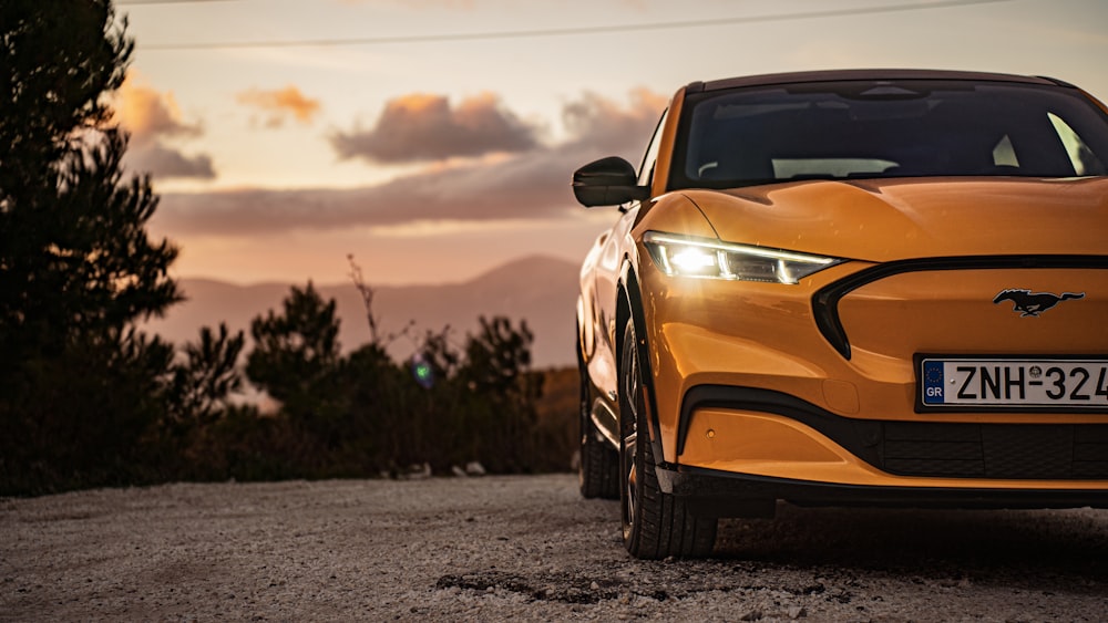 an orange sports car parked on a gravel road