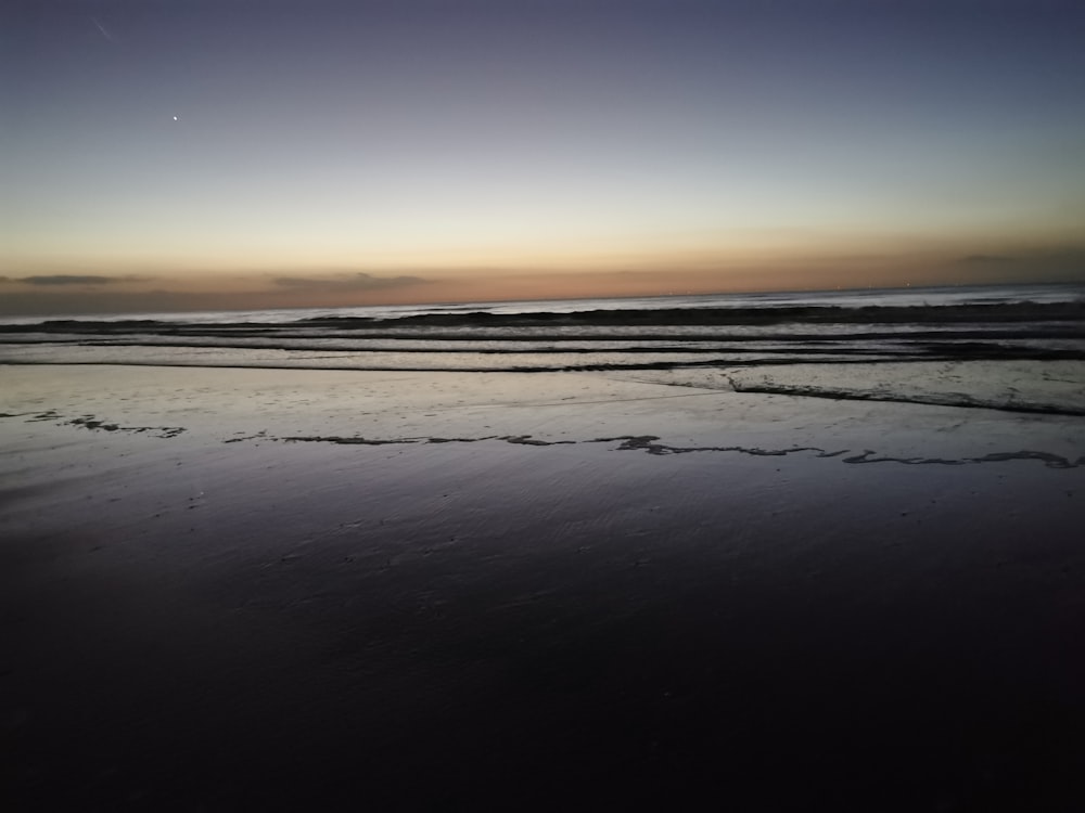 the sun is setting over the water at the beach