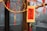A decorative wooden plaque with Chinese calligraphy hangs on a branch adorned with vibrant red tassels and small ornaments. The background appears to be a blurred interior space.