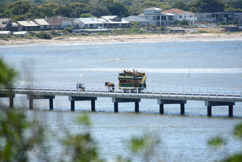 a bus driving across a bridge over a body of water