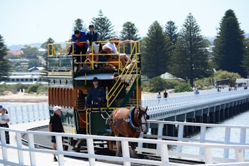 a horse pulling a double decker bus across a bridge