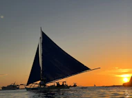 a sailboat sailing in the ocean at sunset