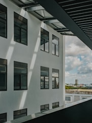 Wide shot of a sleek modern commercial building with a white tensile membrane canopy covering its entrance during daylight
