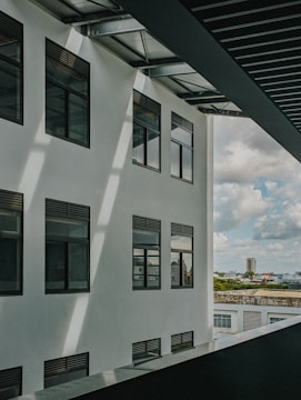 Wide shot of a sleek modern commercial building with a white tensile membrane canopy covering its entrance during daylight