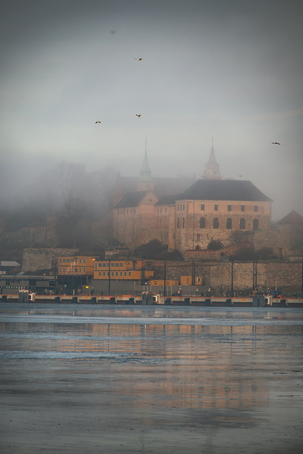 a foggy view of a castle and a body of water