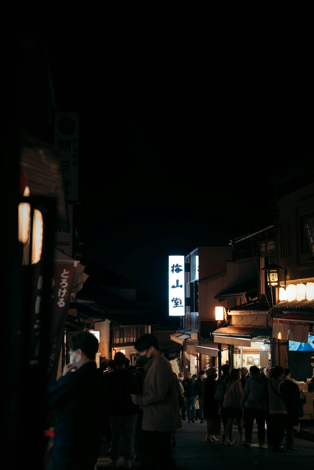 a group of people walking down a street at night