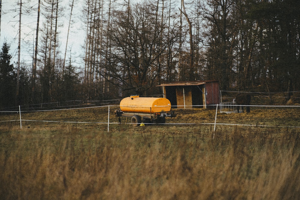 a yellow truck parked in a field next to a fence