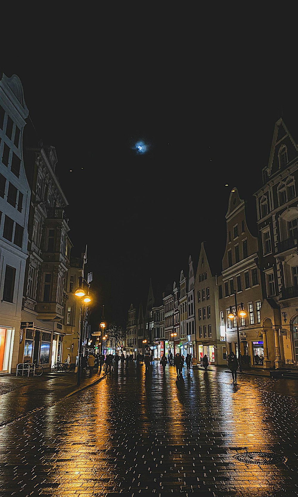 a group of people walking down a street at night