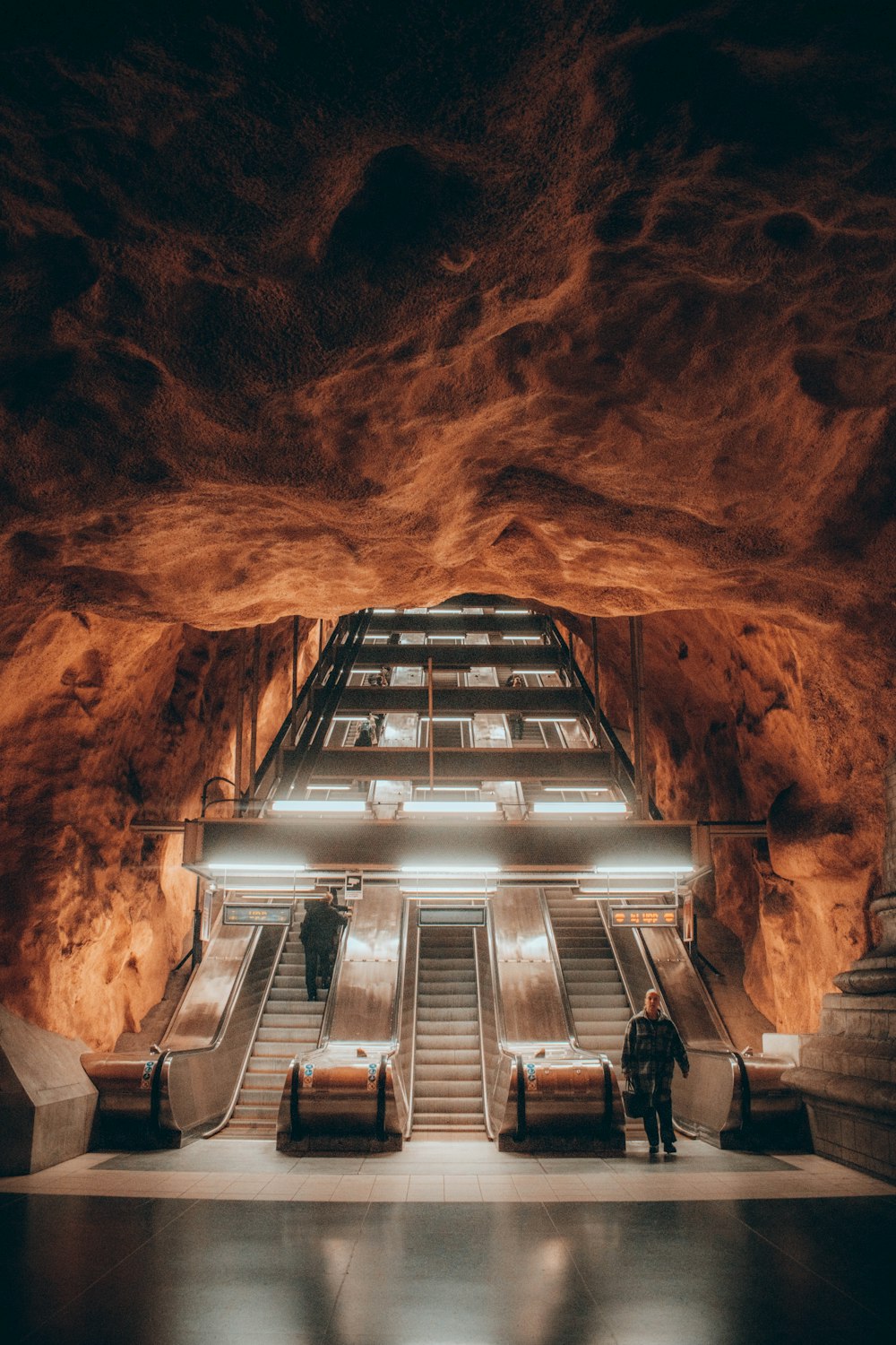 a man standing in a large building with escalators