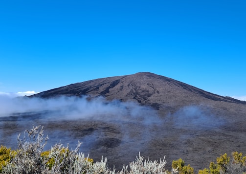 a mountain covered in fog and clouds on a sunny day