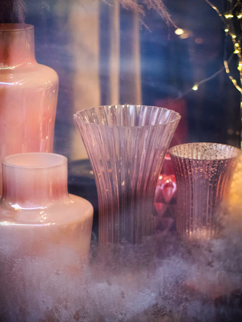 A collection of elegant ceramic vases in soft pastel colors arranged on a wooden shelf