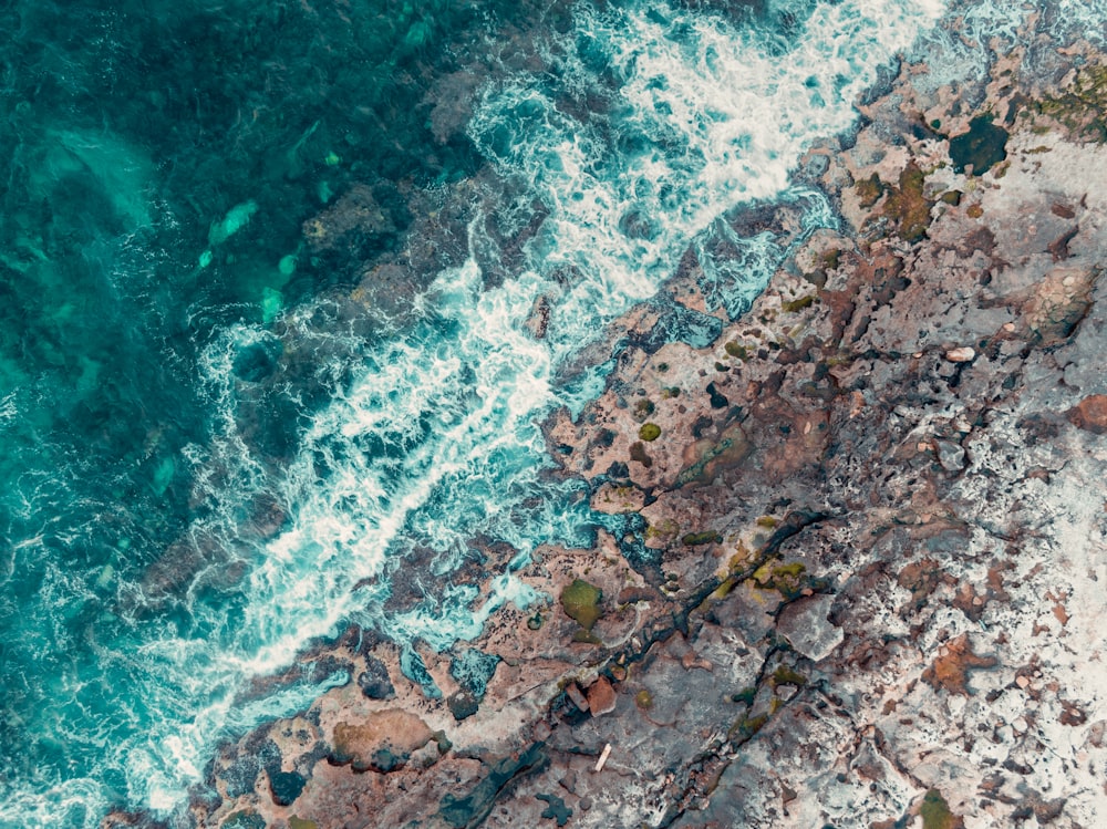 an aerial view of the ocean and rocks