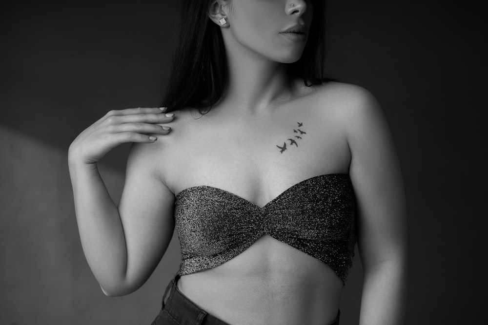 a black and white photo of a woman with a tattoo on her chest