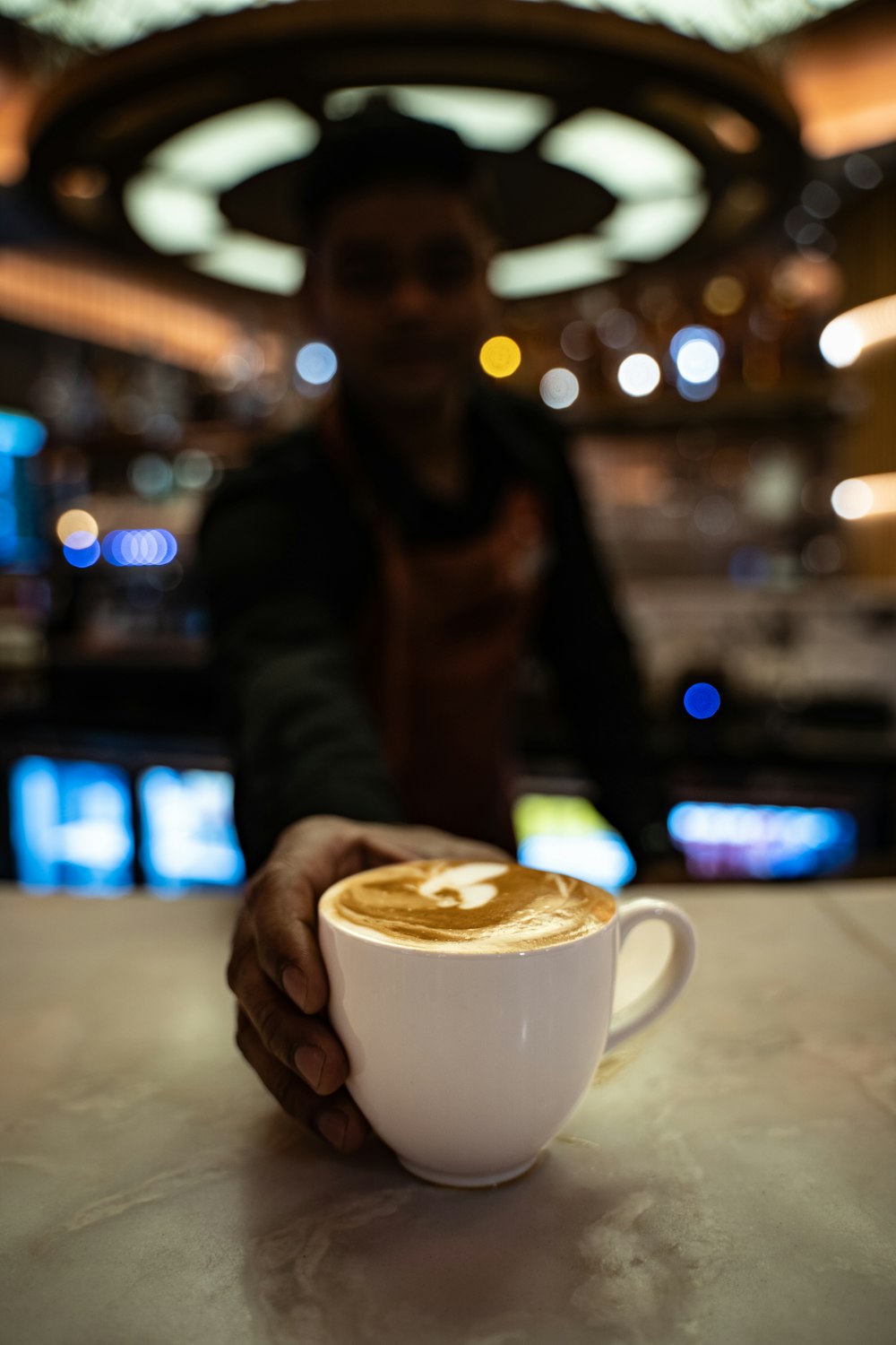 Eine Person, die mit einer Tasse Kaffee an einem Tisch sitzt