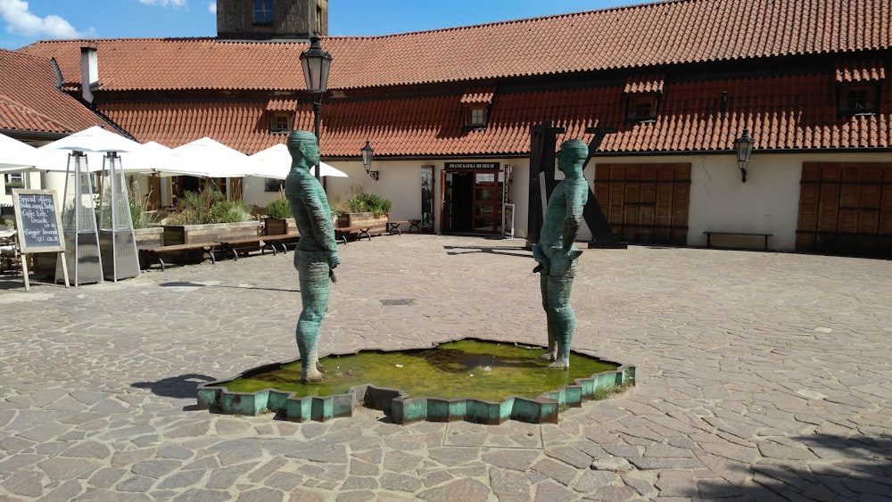 a couple of statues sitting on top of a stone ground