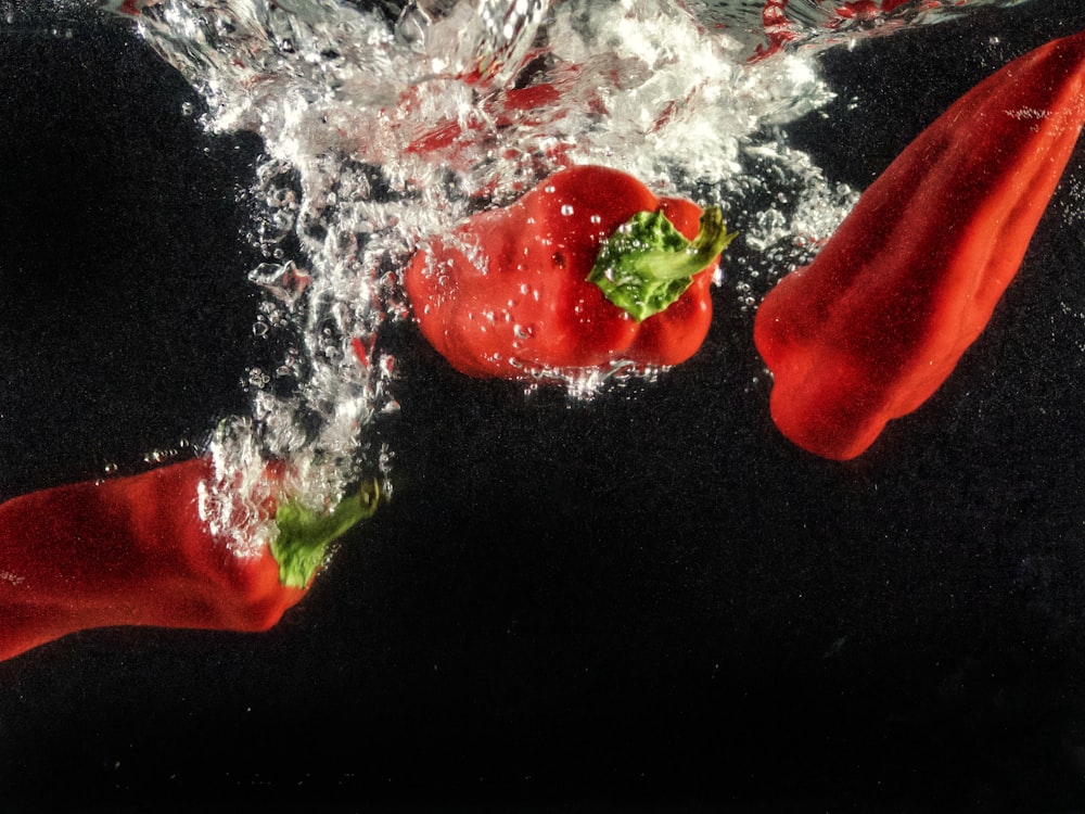 a group of red peppers splashing into the water