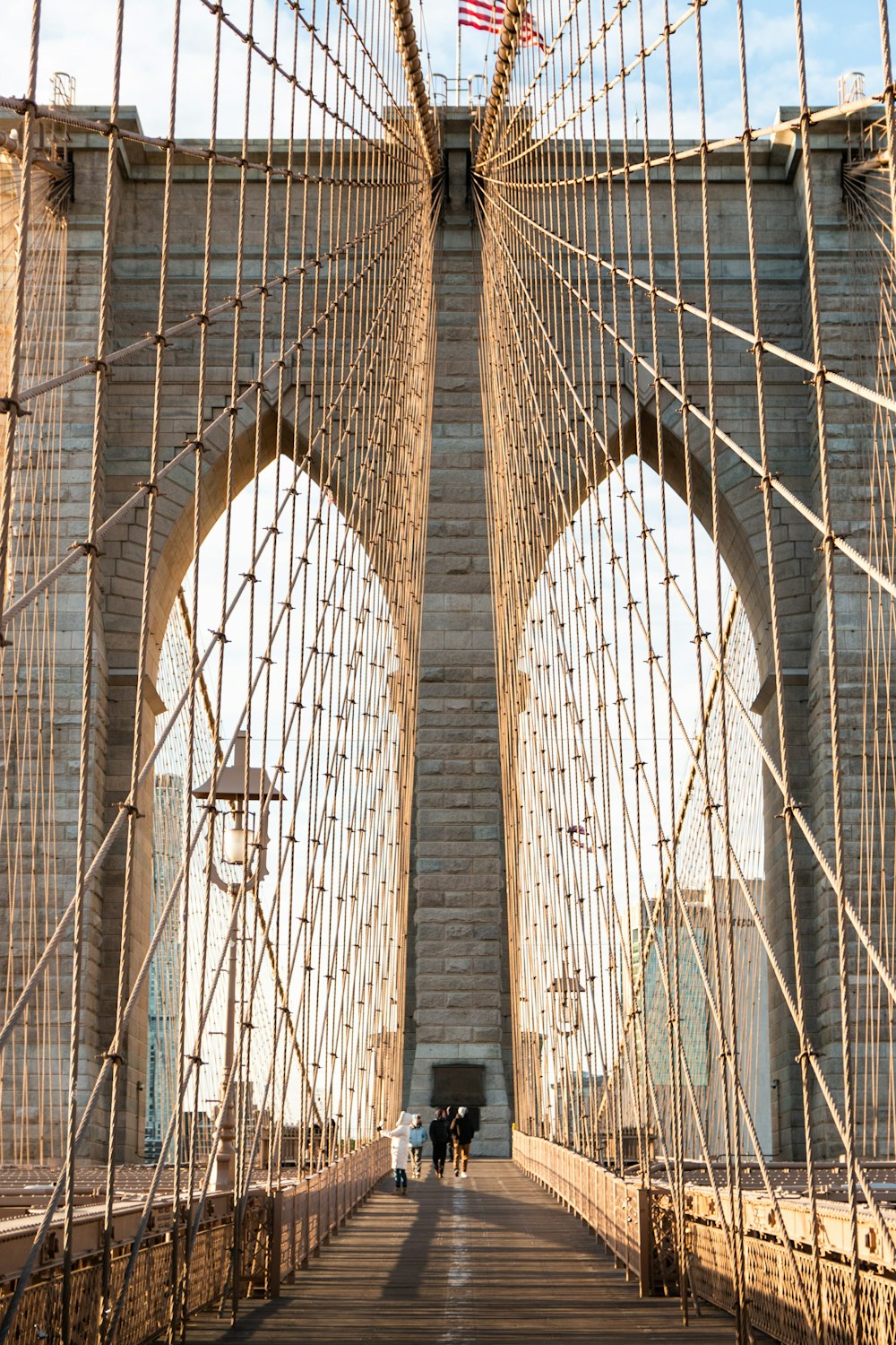 two people walking across a bridge with a flag on top of it