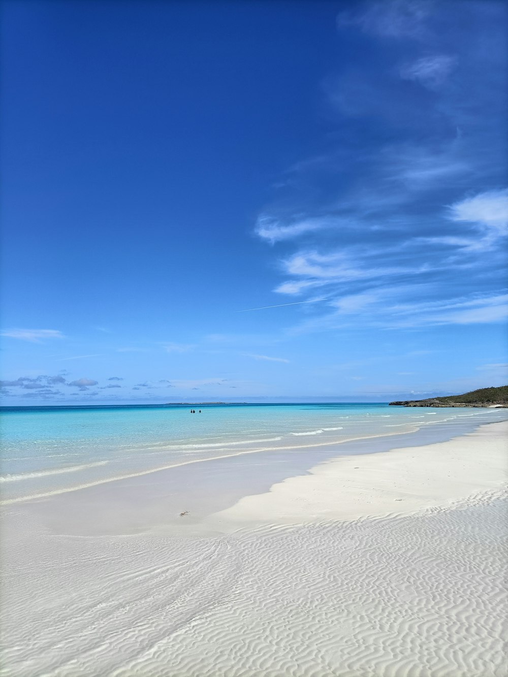 ein Sandstrand mit klarem blauem Wasser und ein Boot in der Ferne