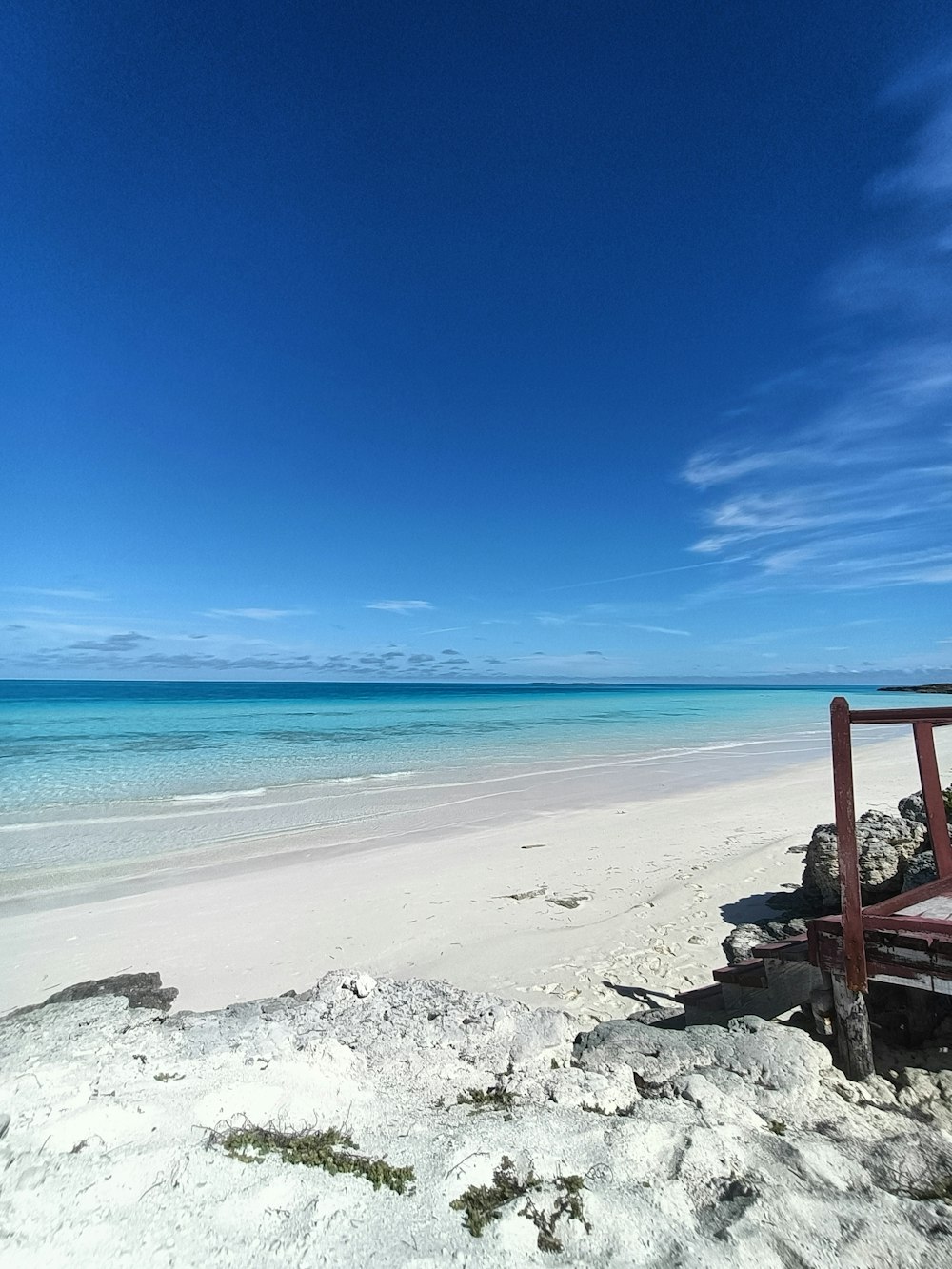 a red bench sitting on top of a sandy beach