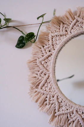 Decorative mirror framed with woven boho-chic macrame hanging on a warm-toned wall in a modern home.