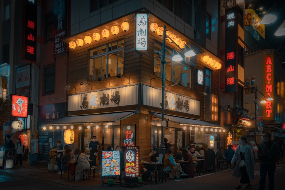 a group of people standing outside of a restaurant at night