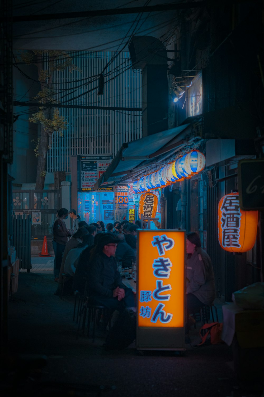 a group of people sitting at a table in a dark alley