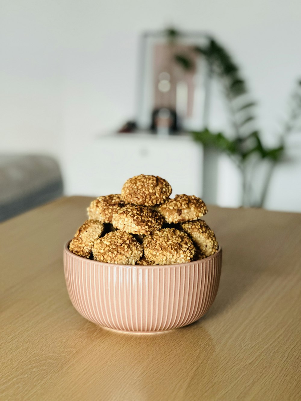 a pink bowl filled with cookies on top of a wooden table