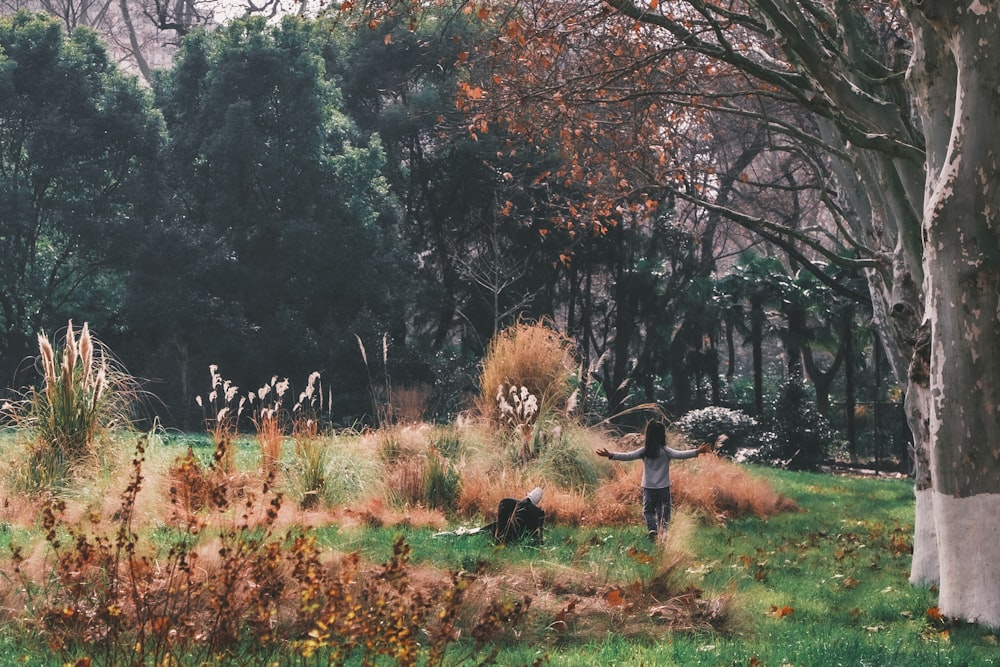 a person standing in a field next to a tree