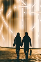 Couple walking hand in hand at sunset, dressed in elegant pieces from Le Monde de Lumina.