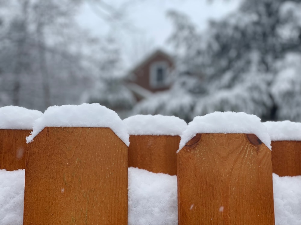 a wooden fence covered in snow in front of a house