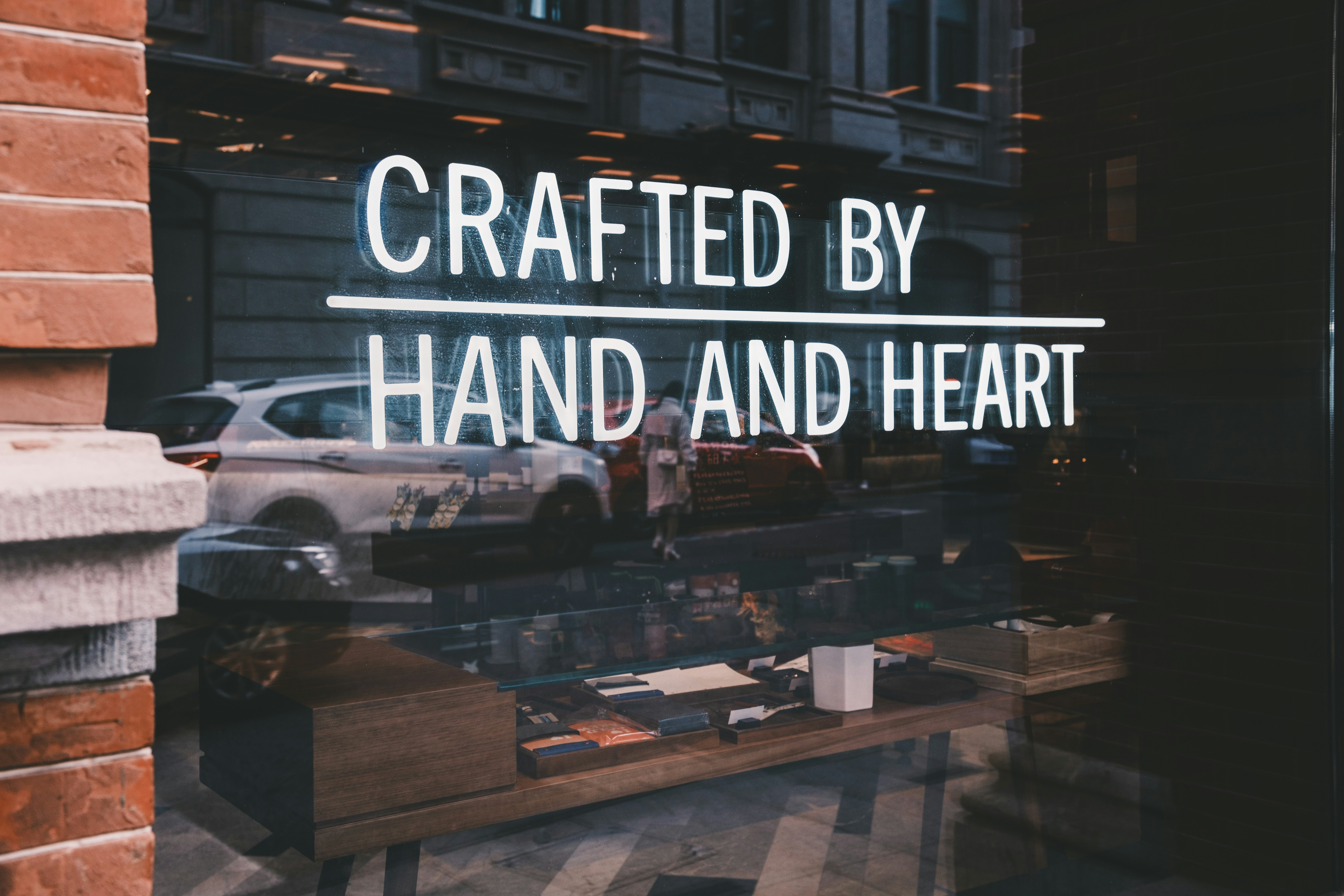 a store window with a sign that reads crafted by hand and heart