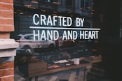 a store window with a sign that reads crafted by hand and heart
