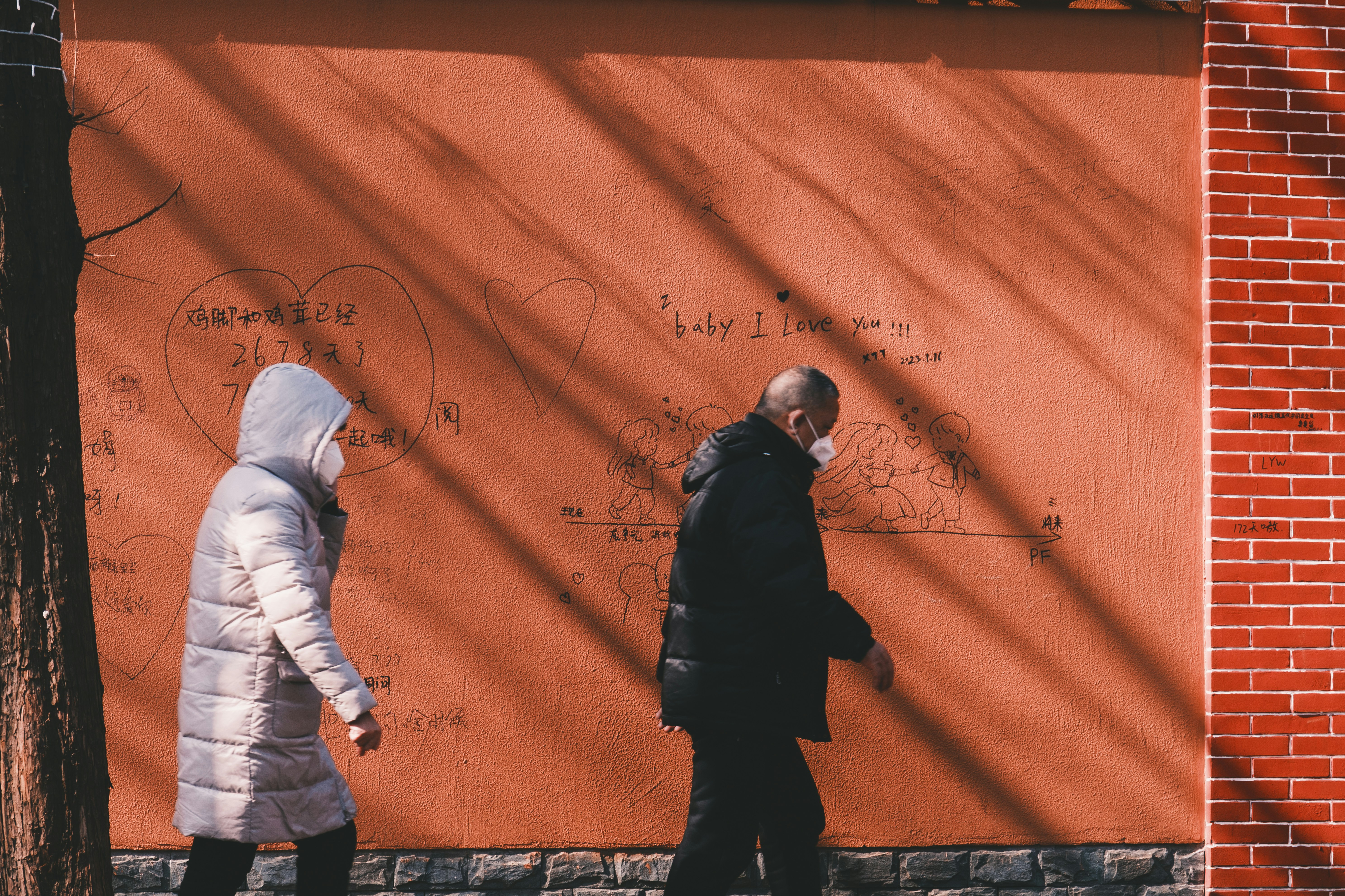 Two people walking past a wall with writing on it photo – Free Shanghai ...