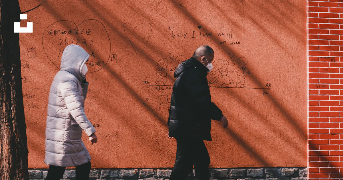 Two people walking past a wall with writing on it photo – Free Shanghai ...