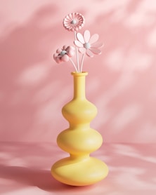 a yellow vase with three flowers in it