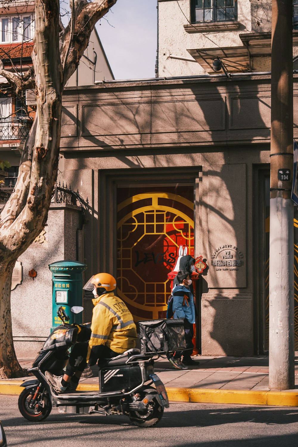 a man riding a motorcycle down a street next to a tall building