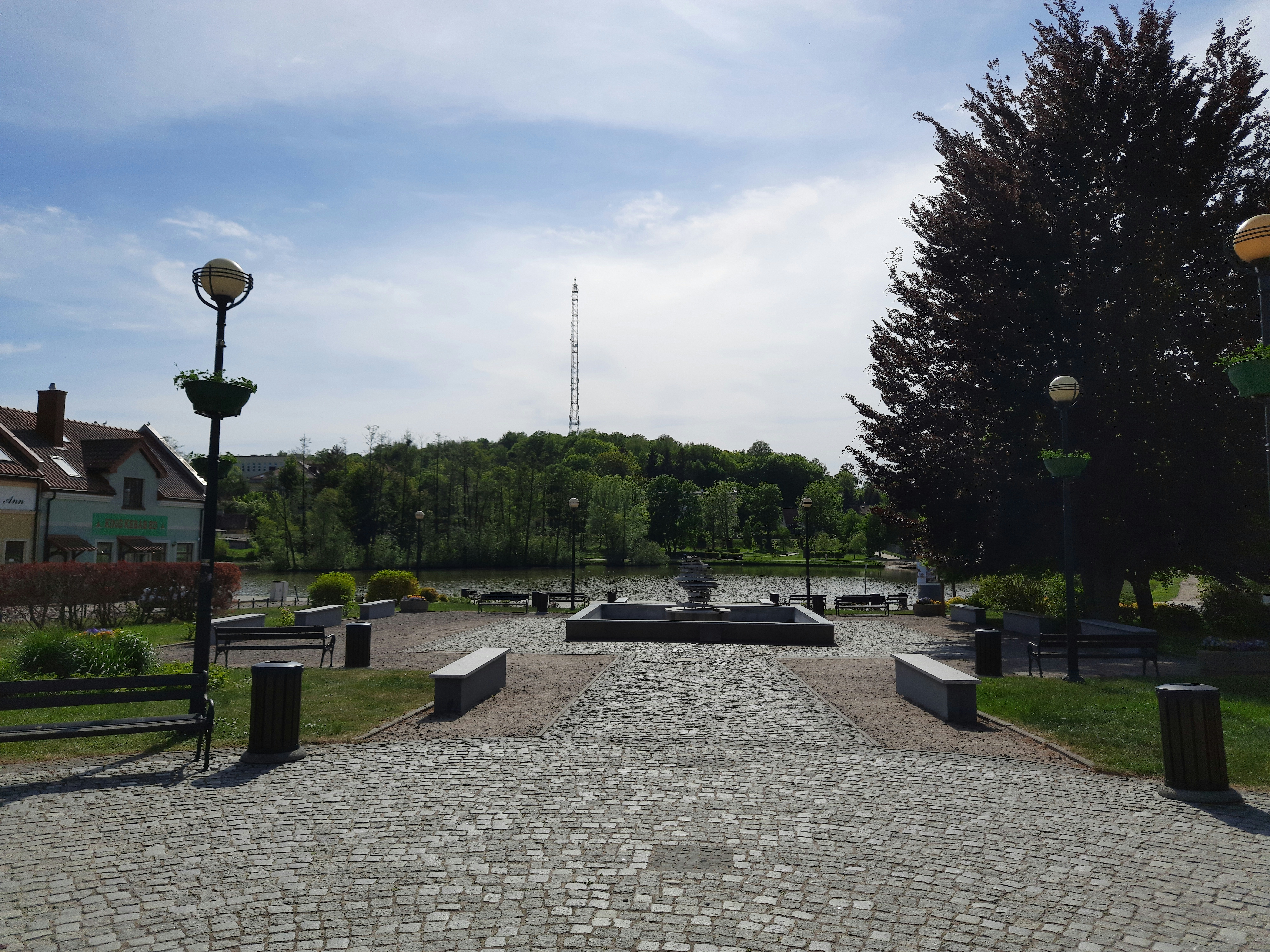a stone walkway leads to a park with a fountain