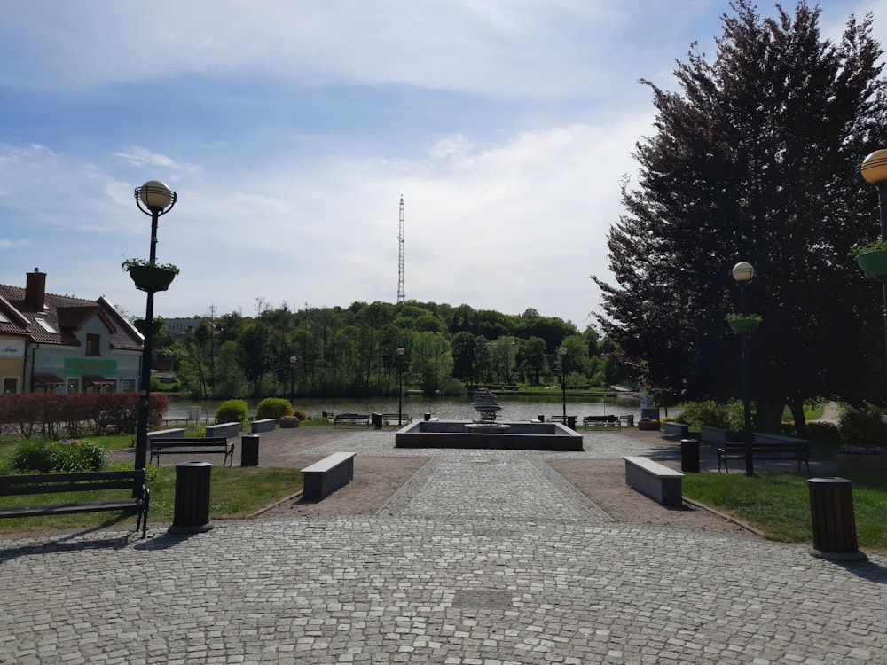 a stone walkway leads to a park with a fountain