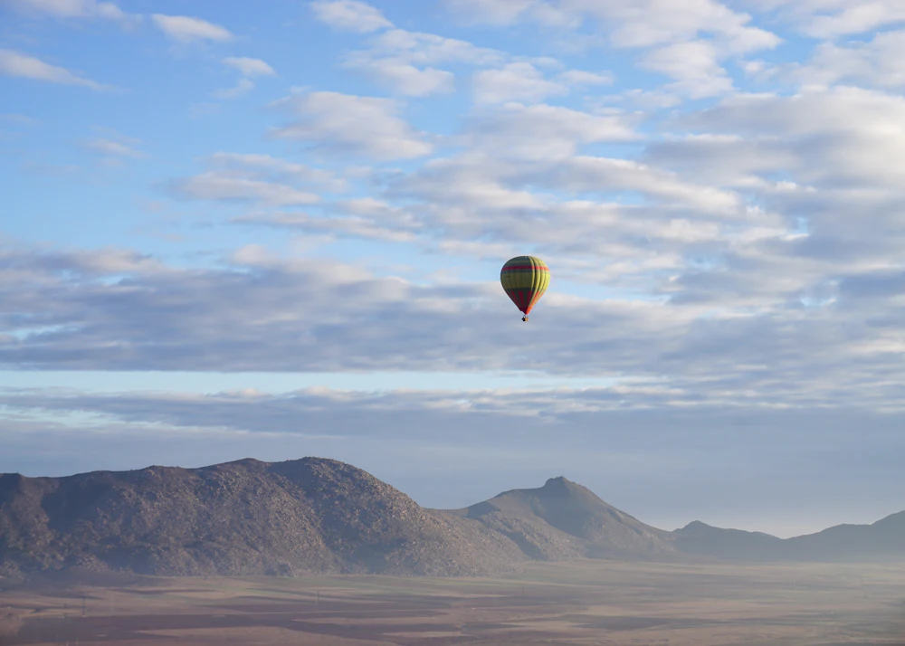 Balloon flying over a mountain range at sunrise