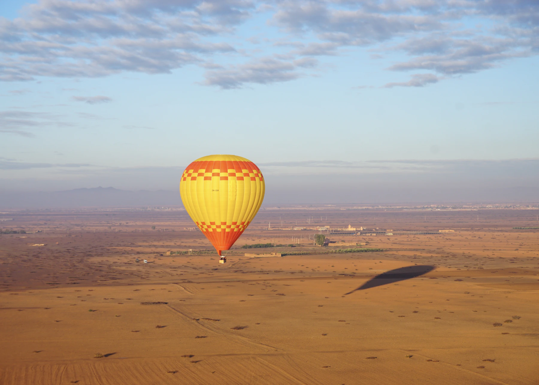 Hot air balloon floating over the plains near Marrakech at sunrise