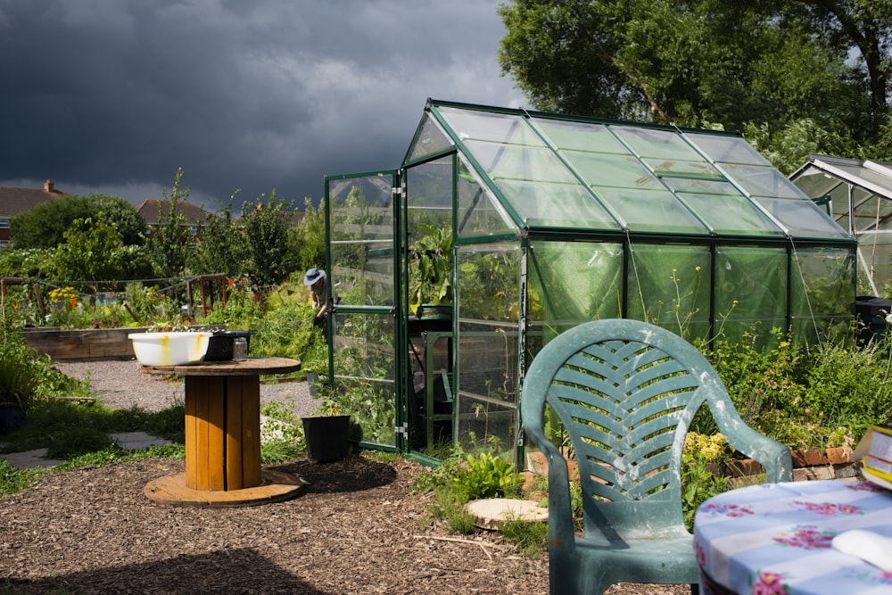 a green house sitting next to a table and chair