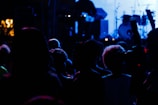 An atmospheric crowd immersed in deep charcoal and soft gold lighting at a live set.