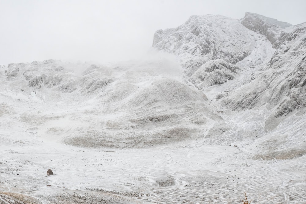 a snow covered mountain range with a few people walking in the snow