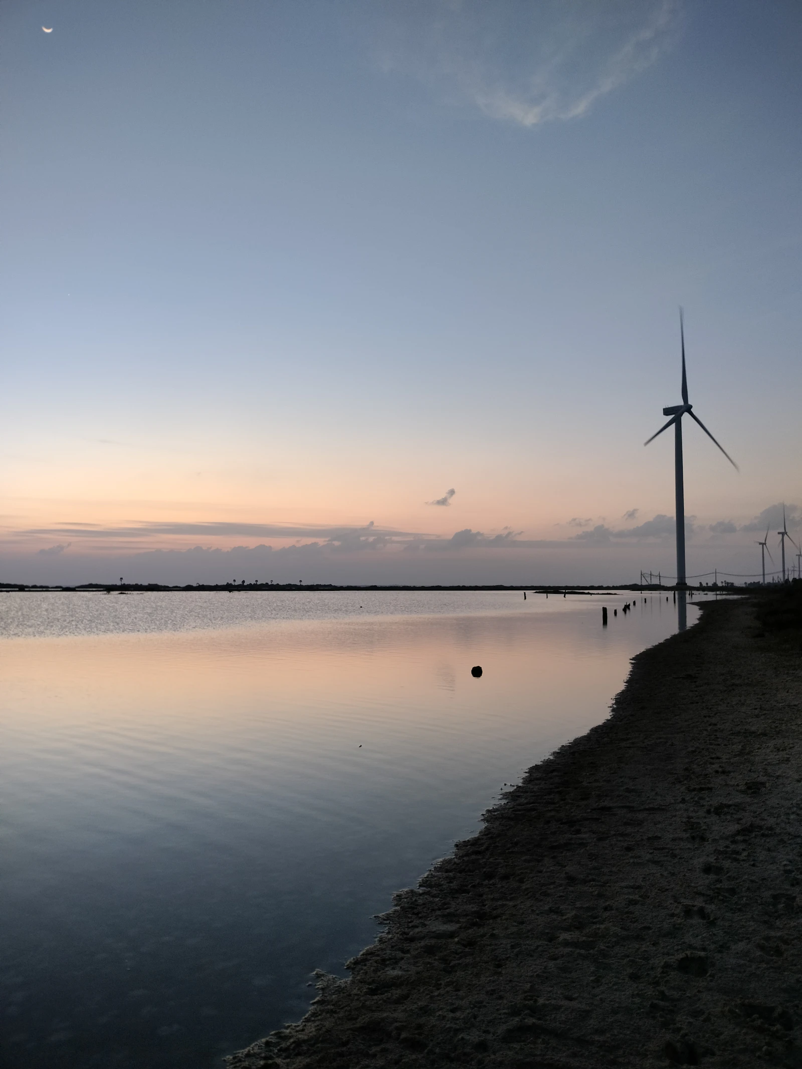 Wide inland reservoir with a windmill on the horizon