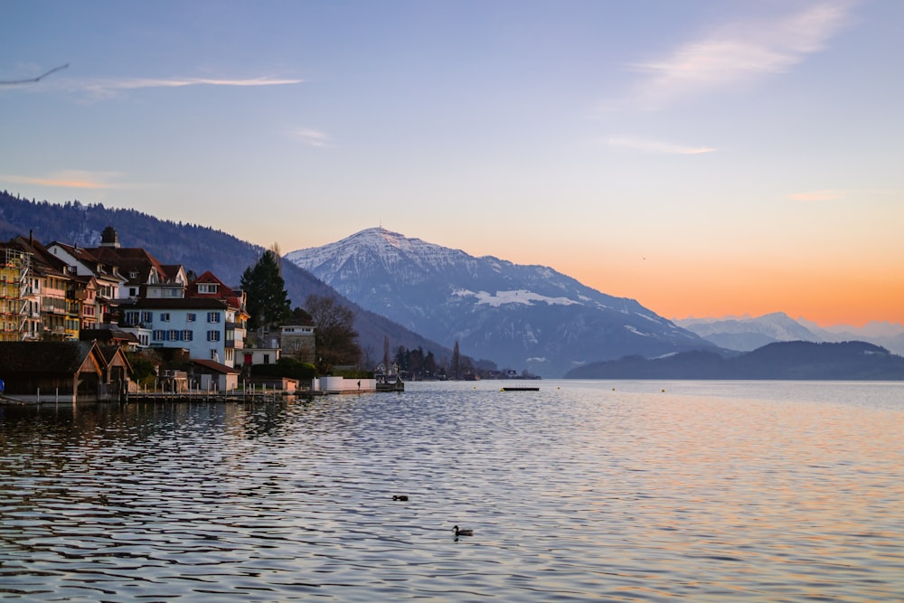 a body of water with houses and mountains in the background