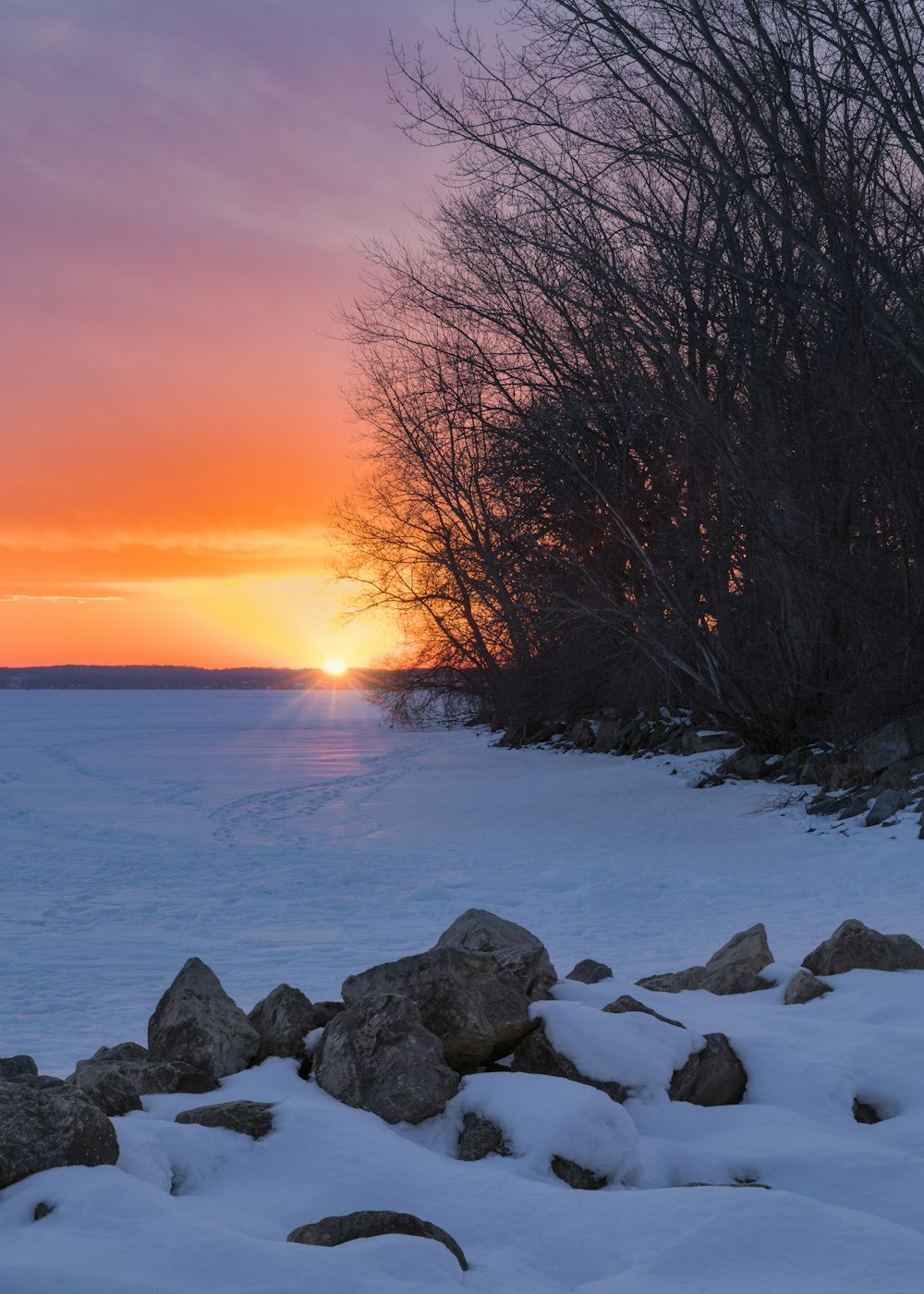 the sun is setting over a frozen lake