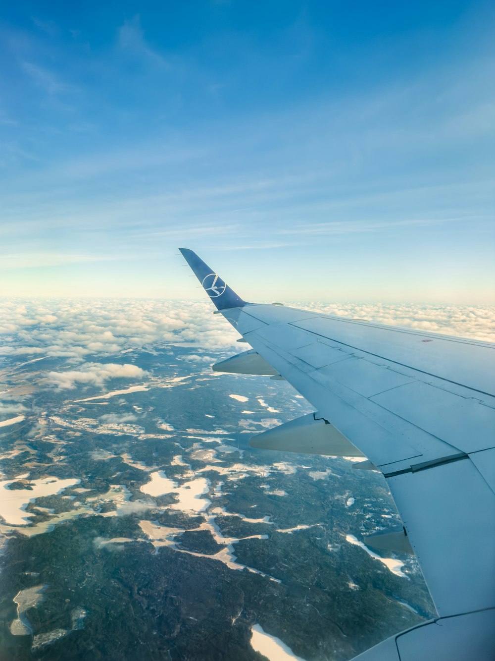 a view of the wing of an airplane flying over the land