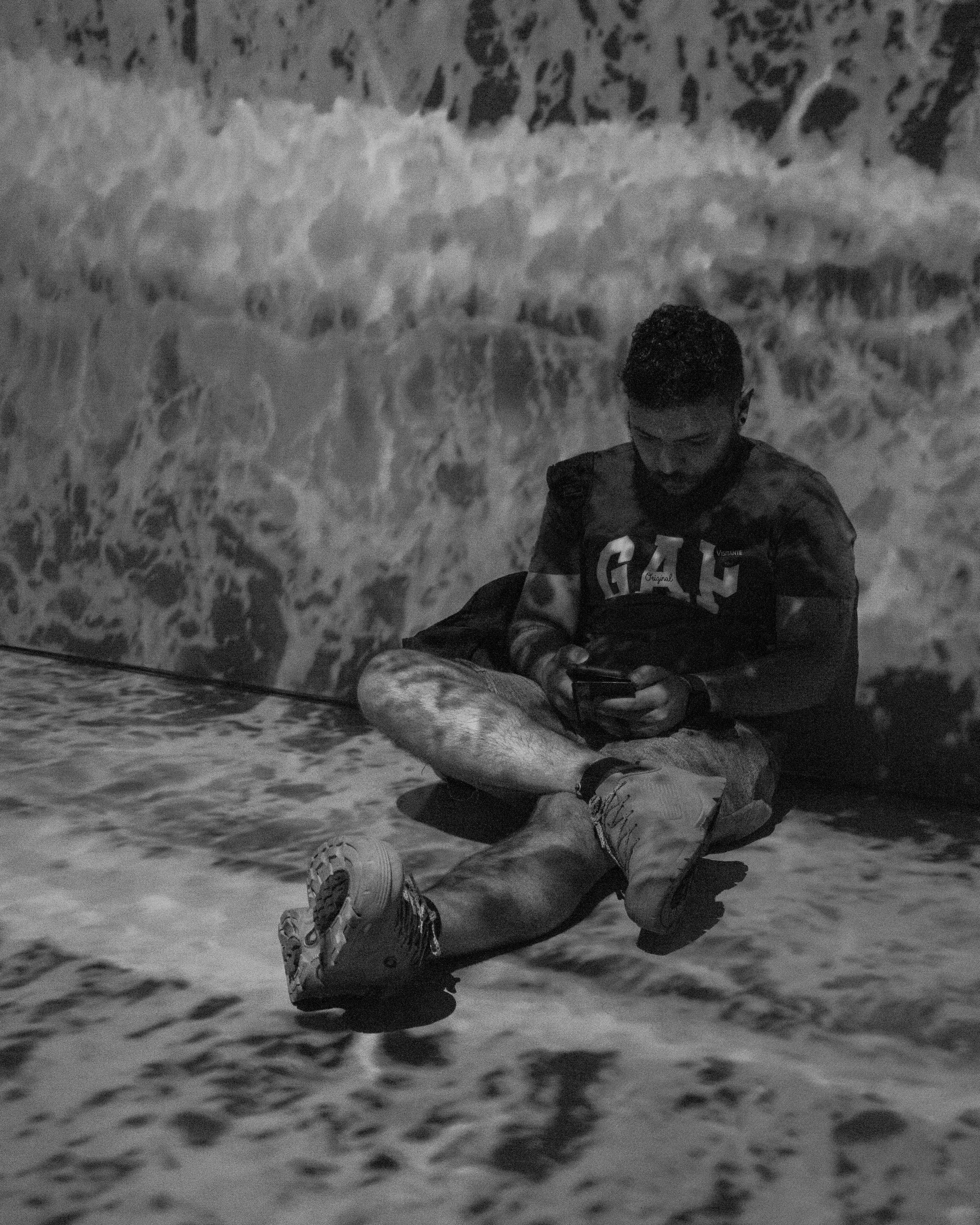 a man sitting on the beach looking at his cell phone